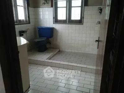 Spacious bathroom with tiled flooring and elevated toilet area.
