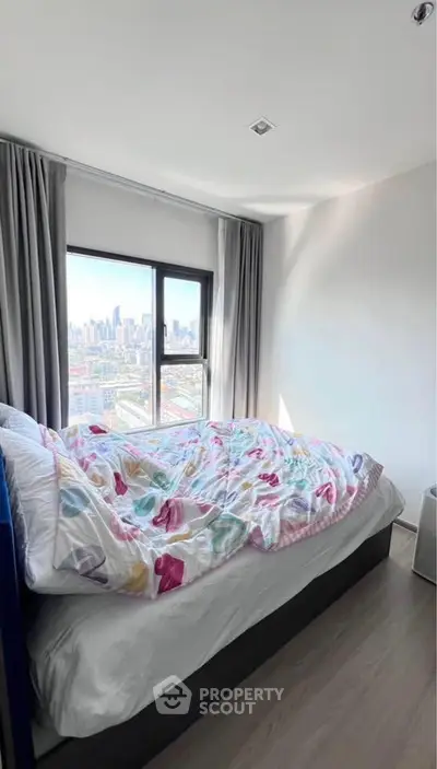 Bright bedroom with city view, featuring cozy bed and large window, perfect for urban living.