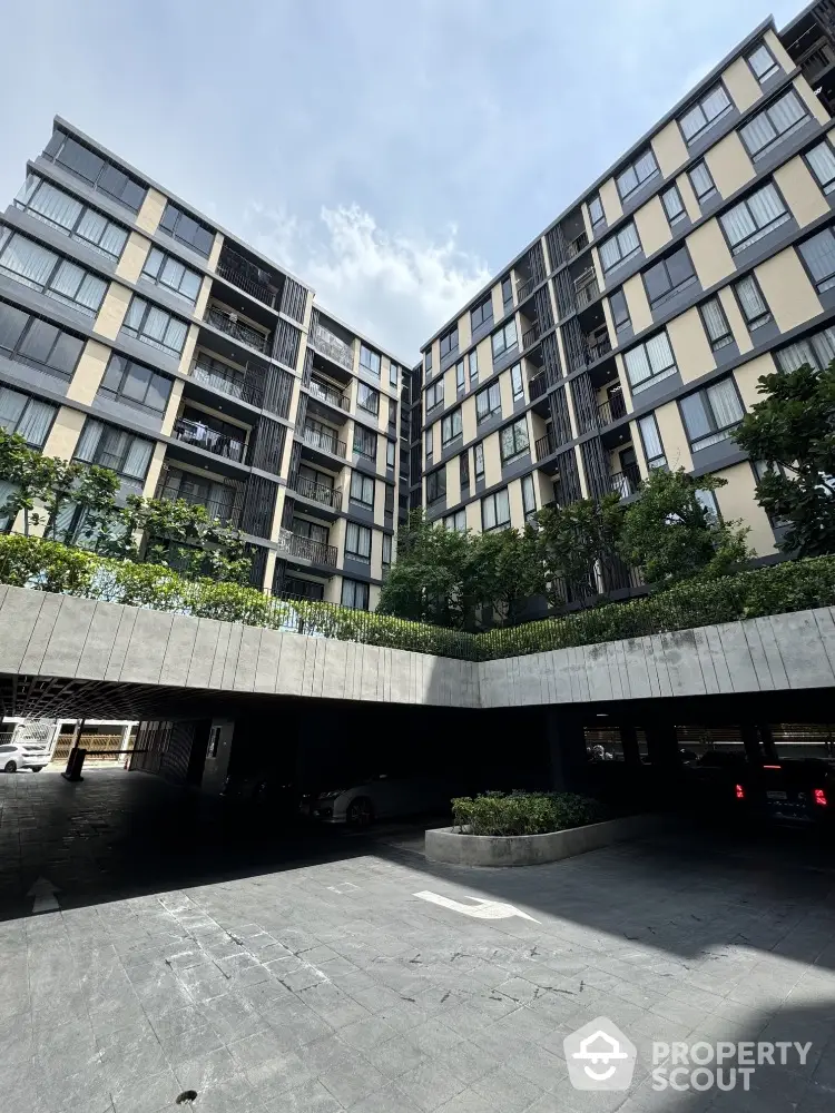 Modern urban apartment building with lush greenery and spacious parking area