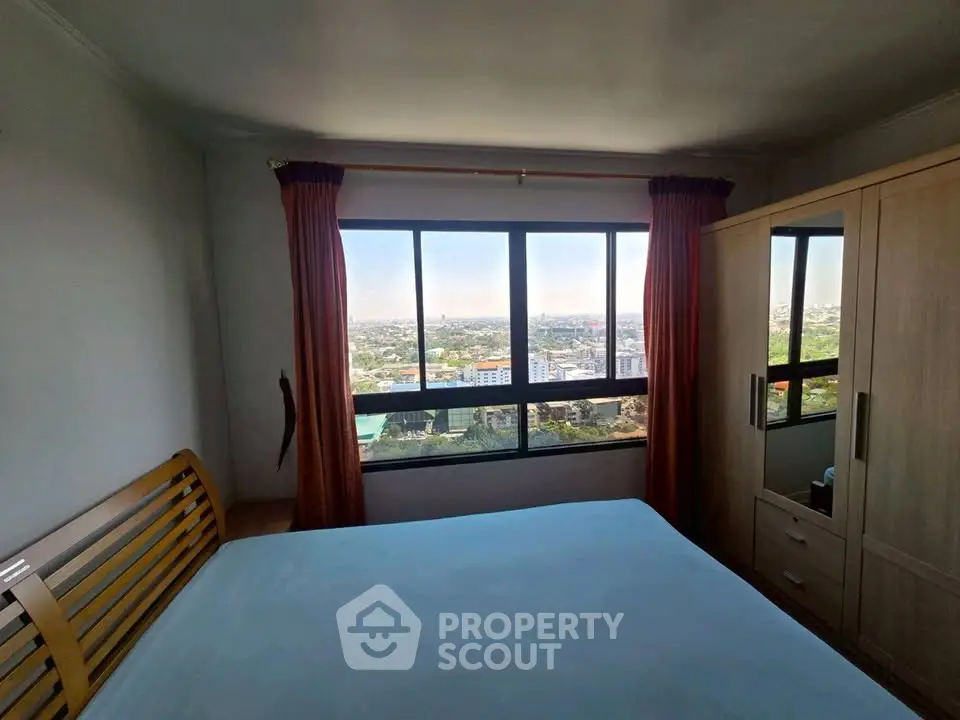 Spacious bedroom with stunning city view from large window, featuring modern wooden furniture.