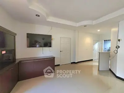 Spacious living room with modern design and wall-mounted TV, perfect for relaxation and entertainment.