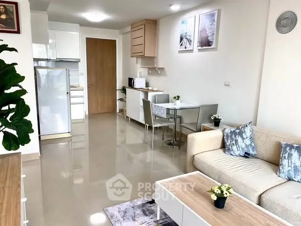 Modern living room with open kitchen, stylish decor, and natural light.