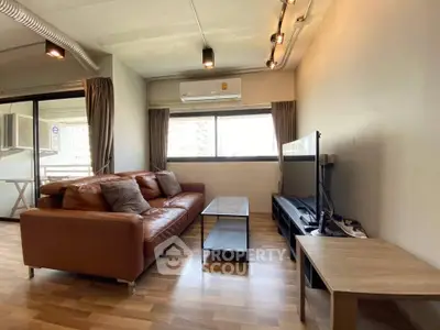 Modern living room with leather sofa and large window, featuring stylish decor and natural light.