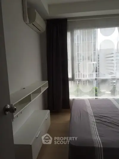Modern bedroom with large window and air conditioning in urban apartment