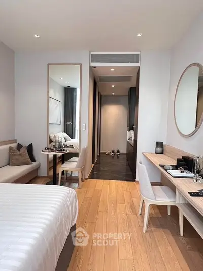 Modern bedroom with elegant decor, featuring a cozy seating area and stylish wooden flooring.