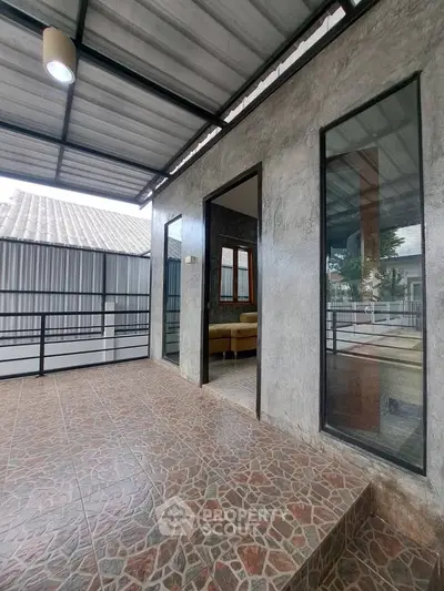 Modern industrial-style patio with tiled flooring and large windows.