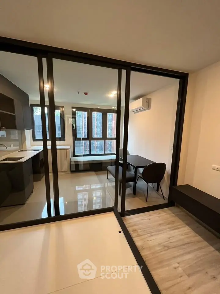 Modern open-plan living room with glass partition and sleek kitchen design