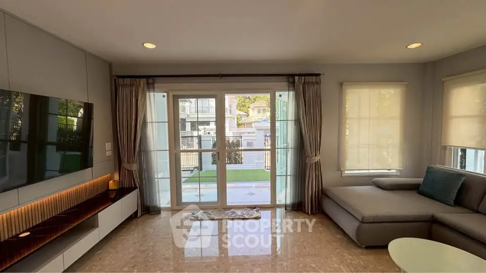 Spacious living room with modern decor and large windows overlooking garden