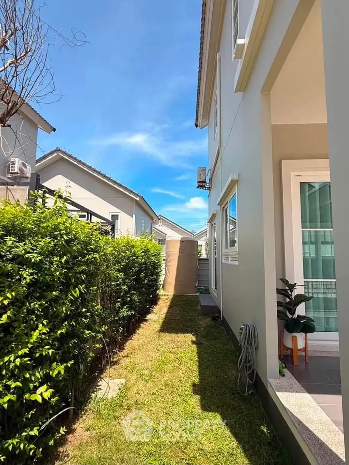 Charming side view of modern house with lush greenery and clear blue sky.