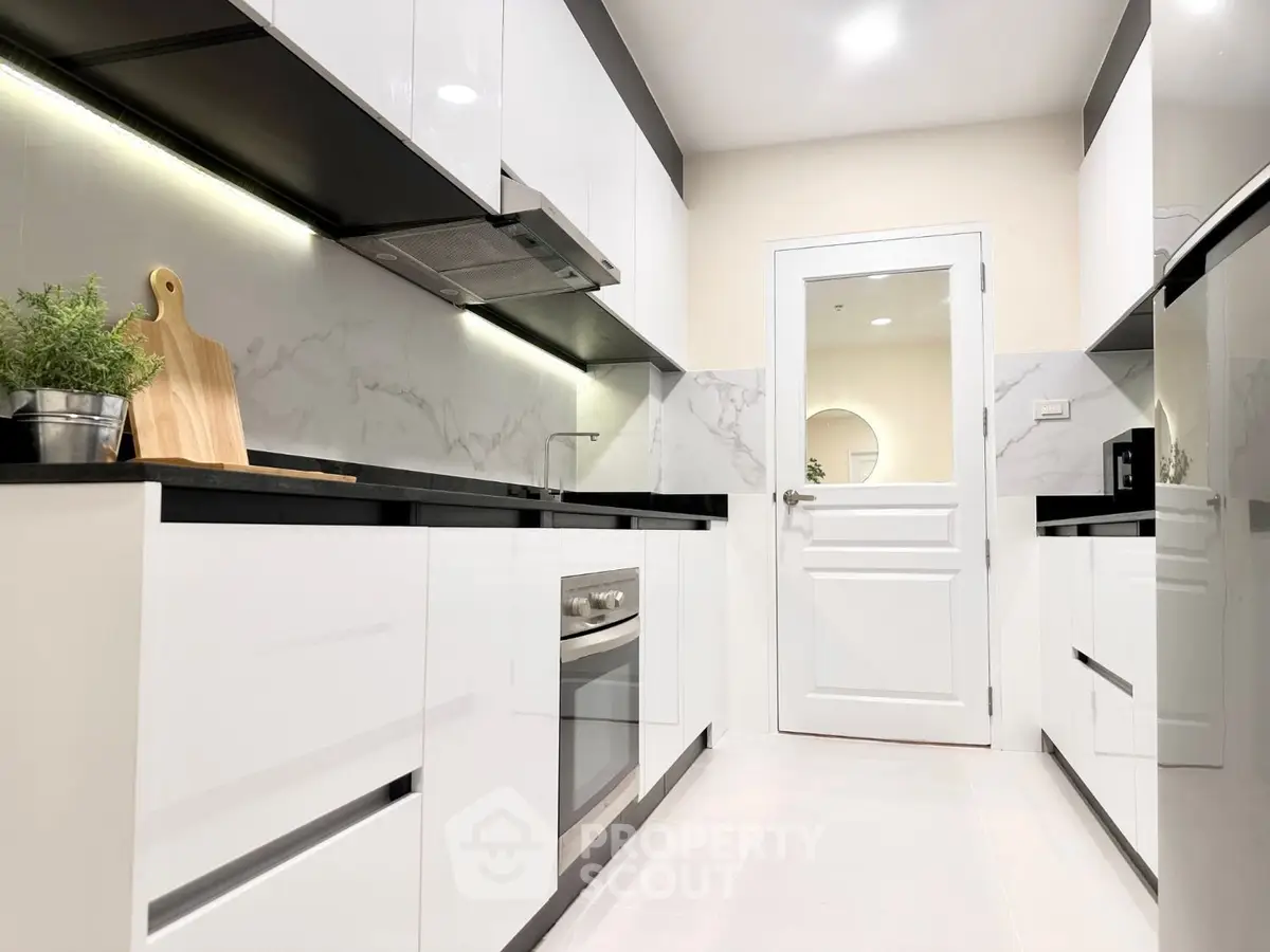 Modern kitchen with sleek white cabinets and built-in oven in a stylish apartment.