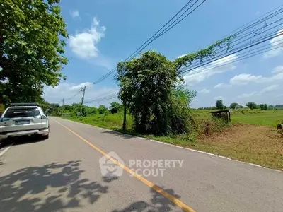 Scenic rural road with lush greenery and clear blue sky, ideal for countryside living.