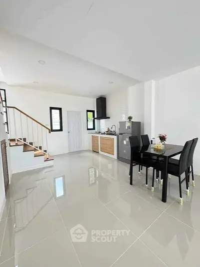 Modern open-plan kitchen and dining area with sleek design and staircase.