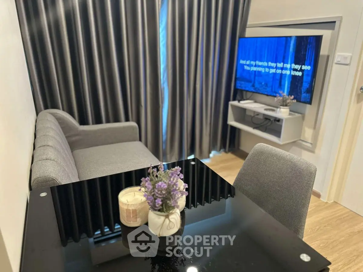 Modern living room with sleek black table and cozy gray sofa, featuring a wall-mounted TV.