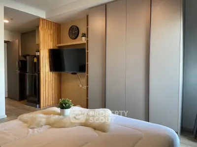 Modern bedroom with sleek design, wall-mounted TV, and cozy decor in a stylish apartment.