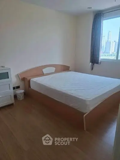 Cozy bedroom with city view, featuring a comfortable bed and natural light through the window.