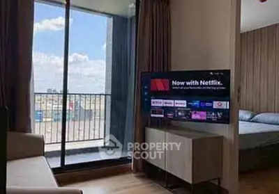 Modern living room with balcony and TV, featuring a cozy sofa and bright natural light.
