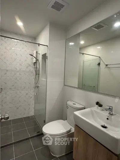Modern bathroom with glass shower and sleek fixtures in contemporary apartment.