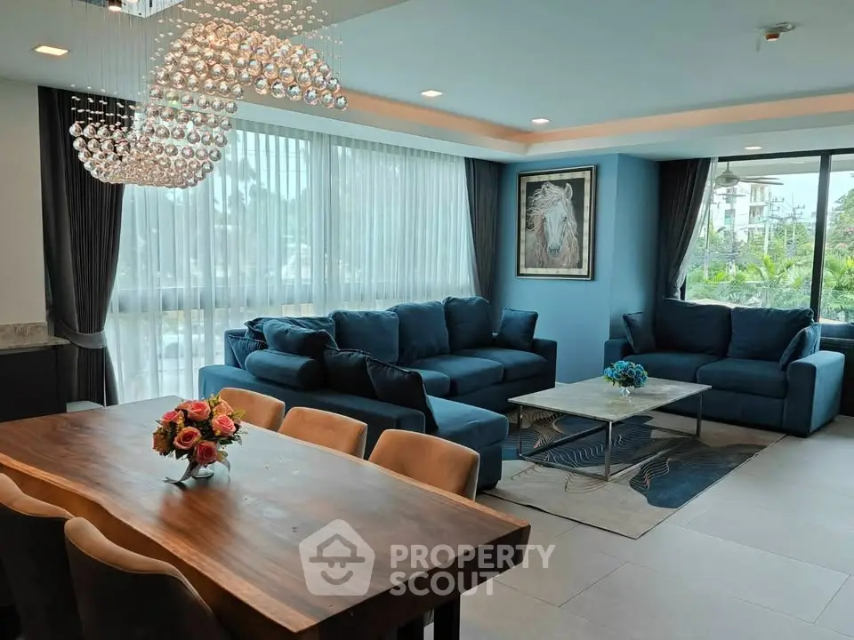 Luxurious living room with elegant chandelier and plush blue sofas, perfect for relaxation and entertaining.