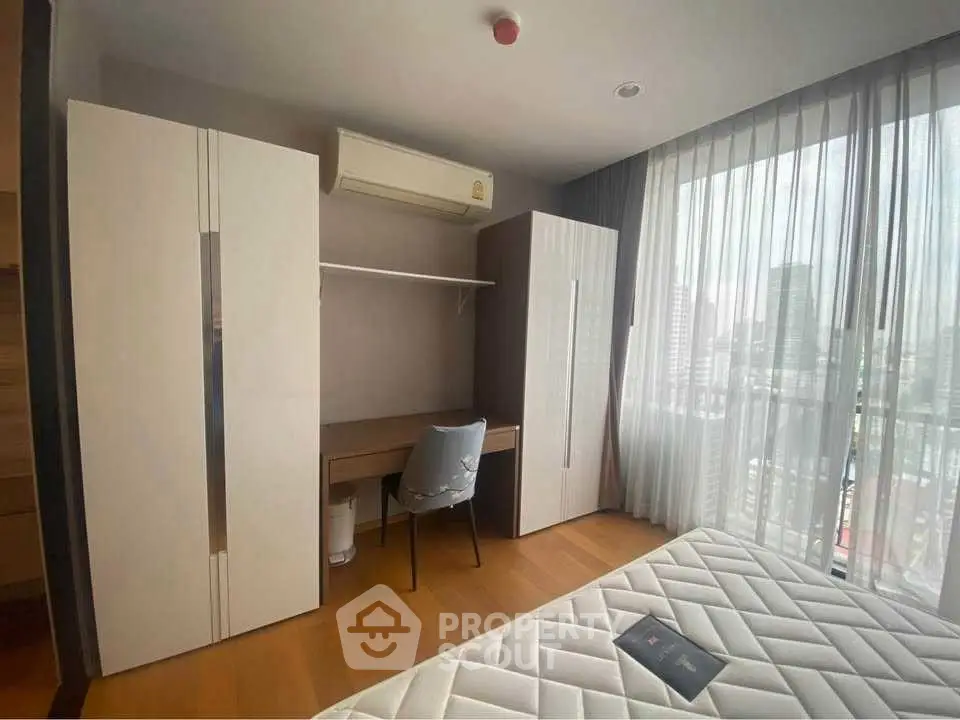 Modern bedroom with city view, featuring sleek furniture and ample natural light.