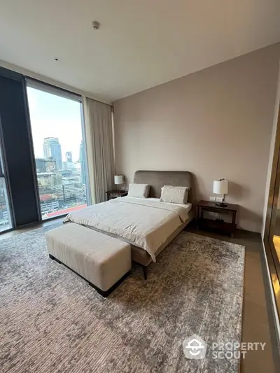 Luxurious bedroom with city view, modern decor, and large windows in high-rise apartment.