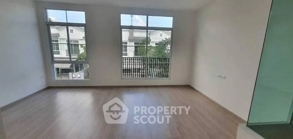 Spacious empty room with large windows and wooden flooring