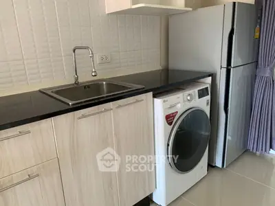 Modern kitchen with sleek cabinets, washing machine, and refrigerator, perfect for urban living.