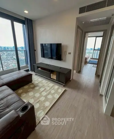 Modern living room with city view, featuring sleek furniture and large windows.