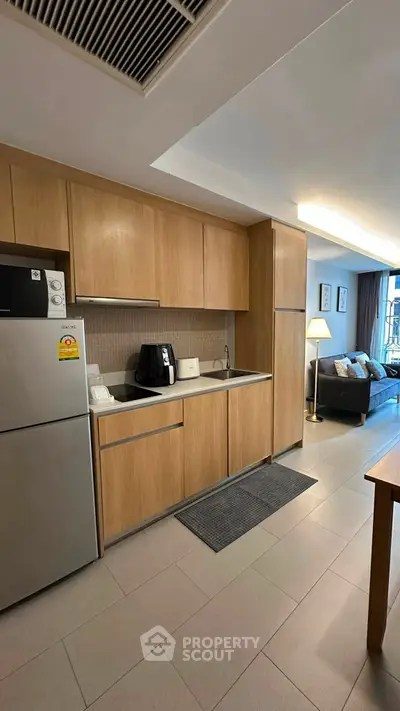 Modern kitchen with wooden cabinets and stainless steel appliances in open layout apartment.