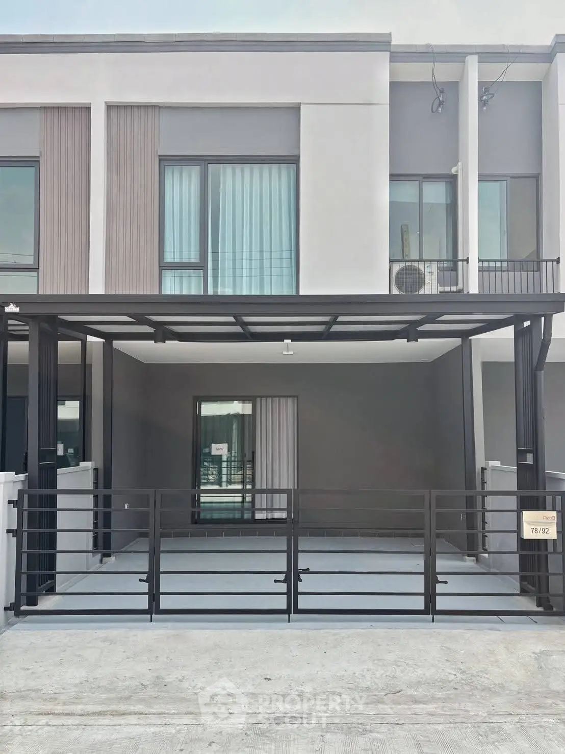 Modern townhouse exterior with sleek design and spacious carport in urban setting.