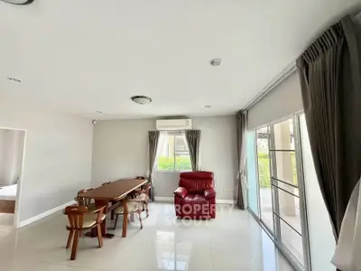 Spacious living room with modern dining set and cozy red armchair, bright natural light