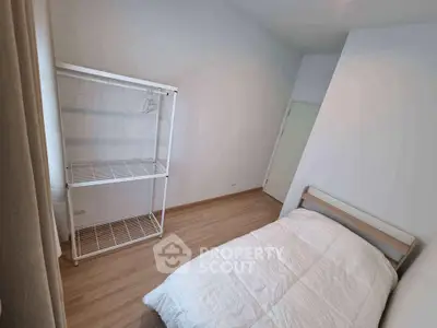 Minimalist bedroom with single bed and white shelving unit