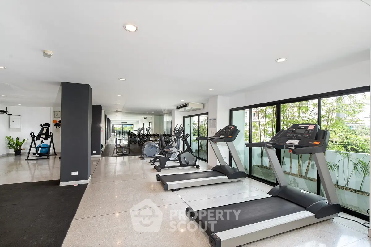 Spacious modern gym with state-of-the-art equipment and large windows offering natural light.