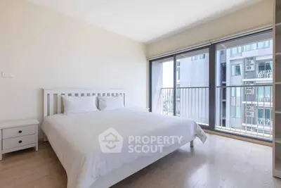Modern bedroom with large windows and balcony view in urban apartment
