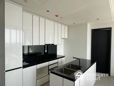 Sleek modern kitchen with high-gloss white cabinetry and contrasting black countertops, featuring state-of-the-art appliances and minimalist design.