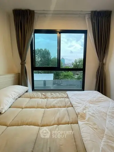 Cozy bedroom with large window offering serene outdoor view