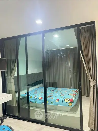 Modern bedroom with glass sliding doors and playful bedding in a stylish apartment.