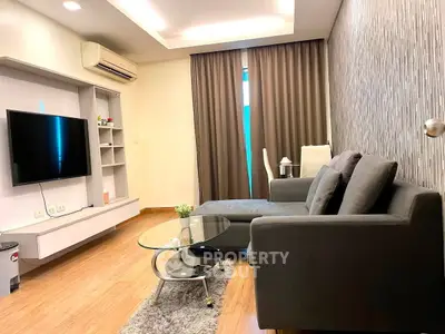 Modern living room with sleek furniture and wall-mounted TV in stylish apartment.
