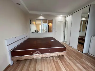 Spacious bedroom with modern design and large mirrored wardrobe in a high-rise apartment.