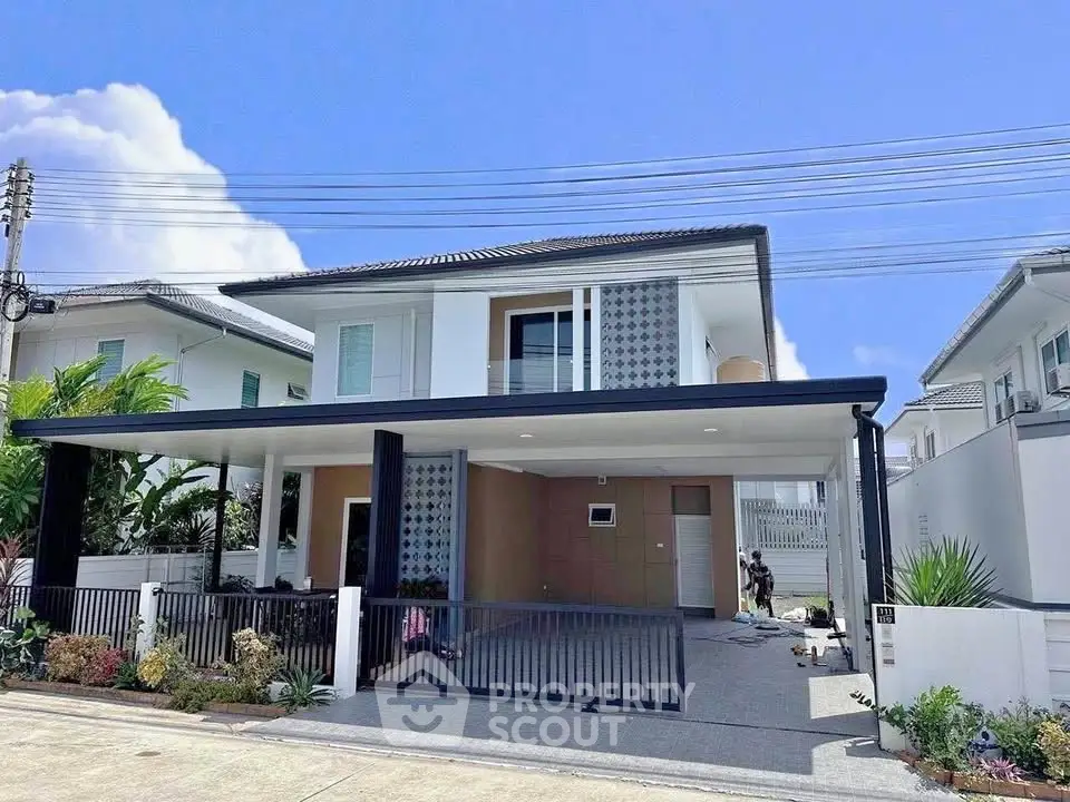 Modern two-story house with sleek design and spacious driveway in a suburban neighborhood.