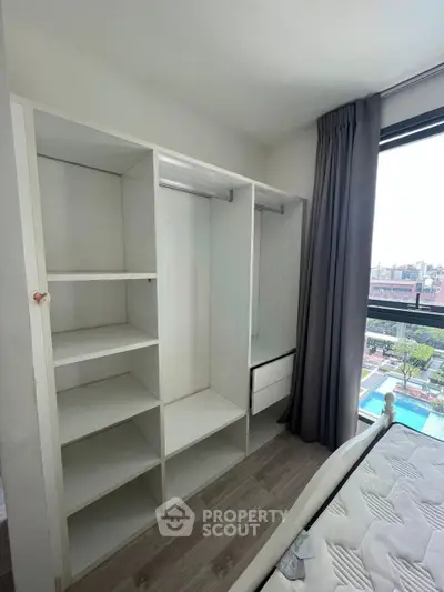Spacious bedroom with built-in closet and large window offering a stunning view of the cityscape and pool.