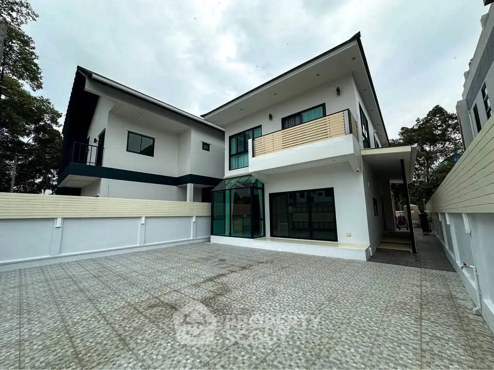 Modern two-story house with spacious driveway and balcony in a serene neighborhood.