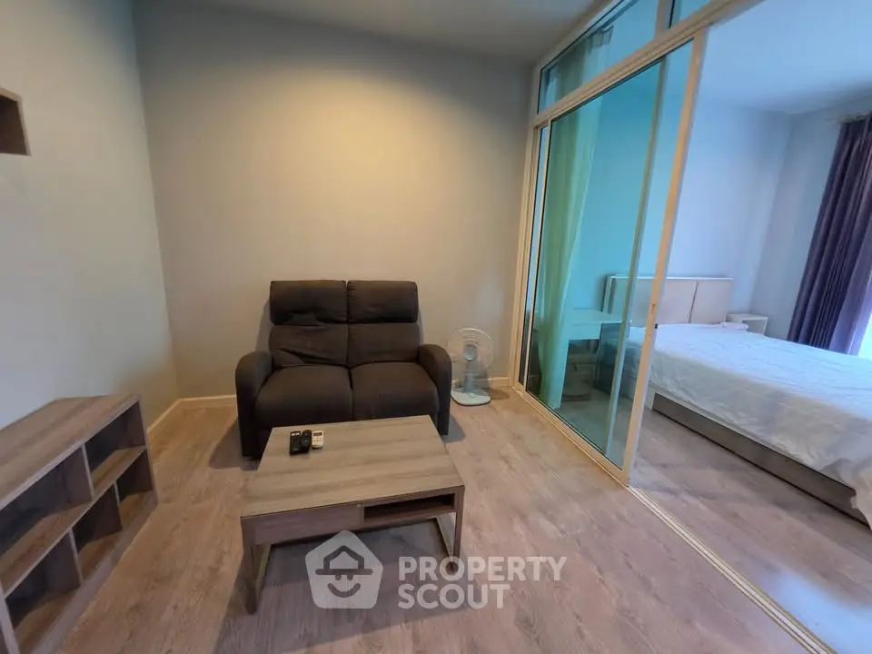 Modern living room with cozy seating and view into a stylish bedroom