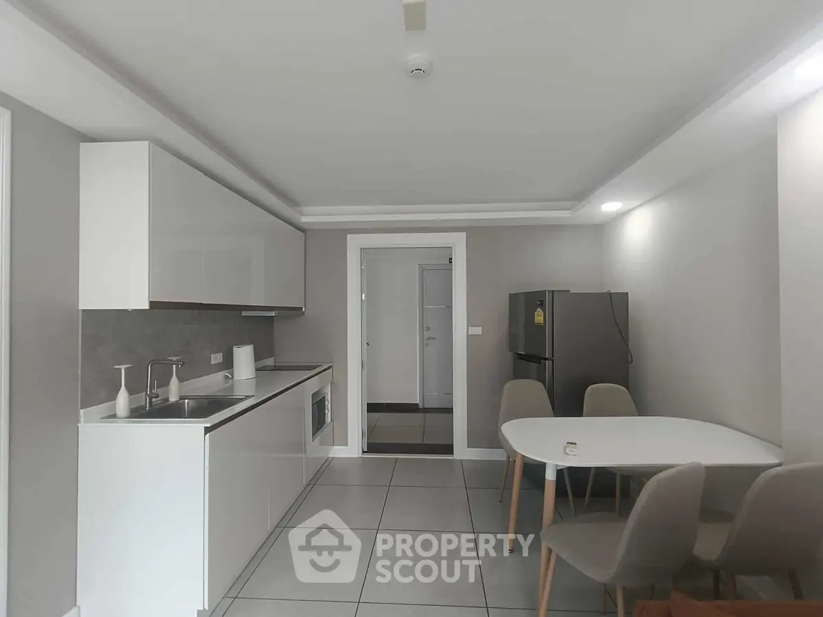 Modern kitchen with sleek white cabinets and dining area in contemporary apartment.