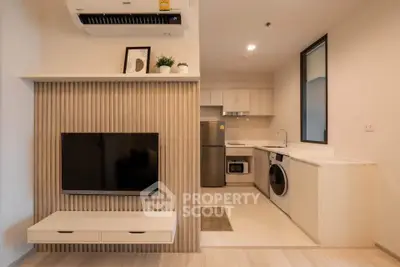 Modern open-layout living room with integrated kitchen, featuring sleek appliances and stylish decor.
