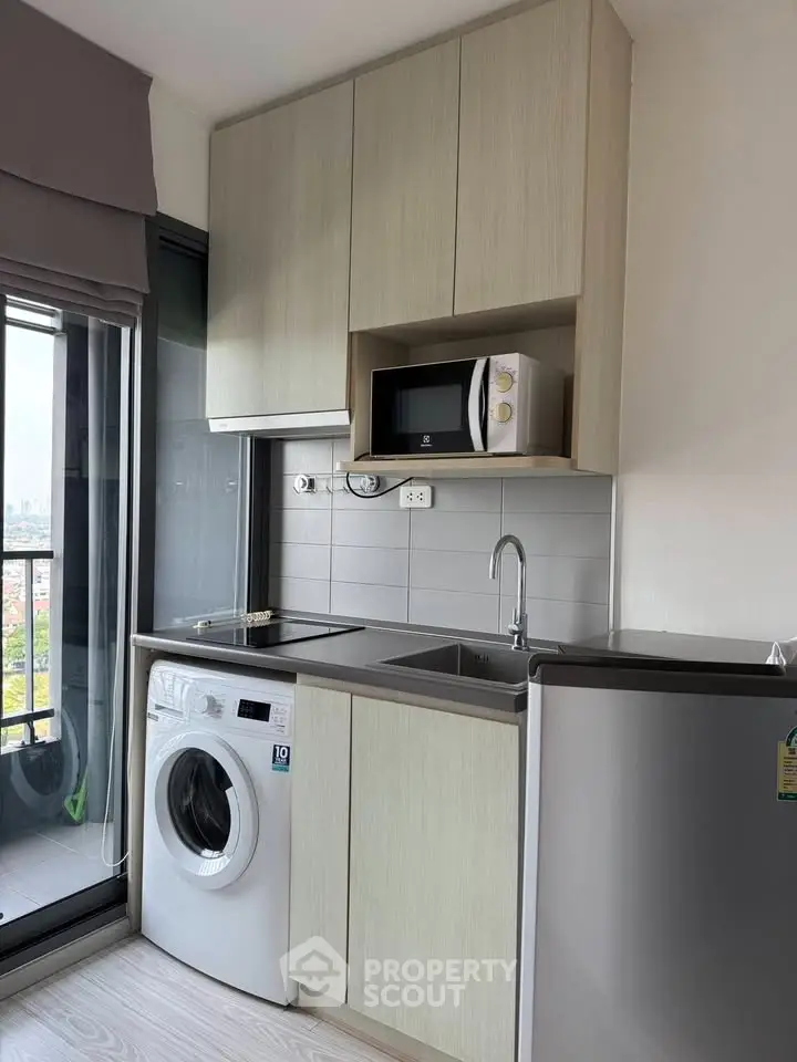 Modern kitchen with washing machine, microwave, and sleek cabinetry in a compact layout.