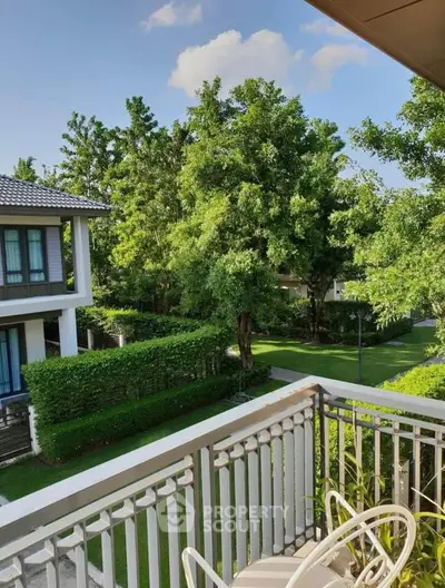Charming balcony view overlooking lush green garden in modern residential area.