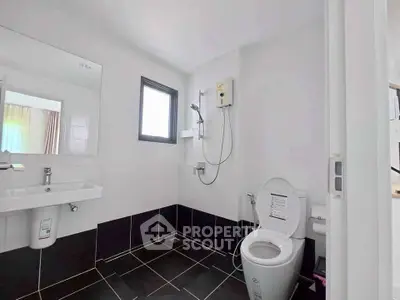 Modern bathroom with sleek black and white tiles, featuring a shower and toilet.