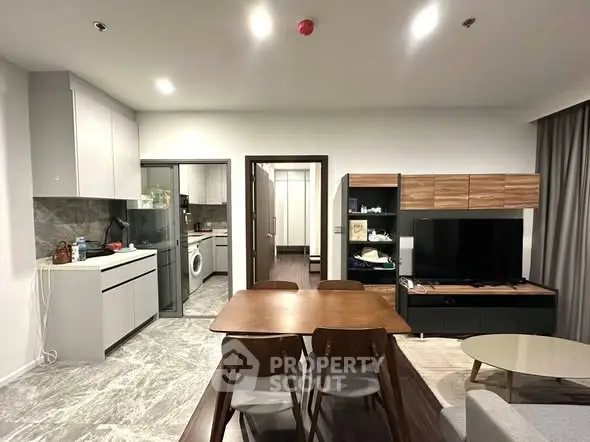 Modern open-plan living room with dining area and kitchen, featuring sleek furniture and contemporary design.