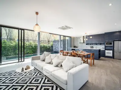 Spacious modern living room with open kitchen and large windows overlooking greenery.