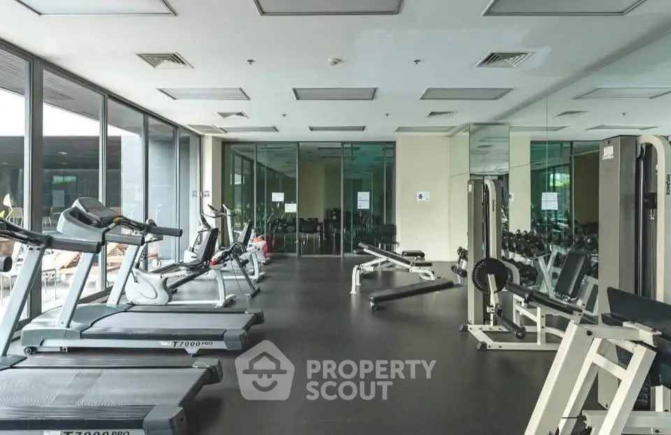 Modern gym with state-of-the-art equipment and large mirrors in a luxury residential building.